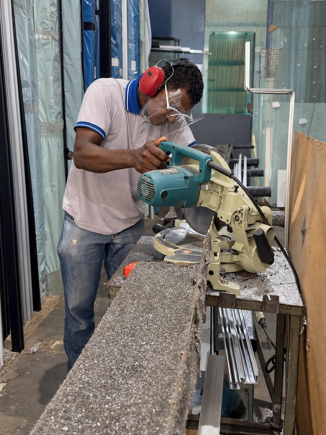 Profissional com protetor facial e abafadores trabalhando no corte de perfis
